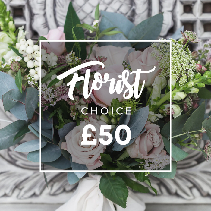 A richly textured, bespoke florist's-choice bouquet is centered in the frame, its soft blush roses and clusters of white berries arranged with an artful, natural economy that reads both sophisticated and relaxed. The rounded rose heads open into layers of delicate petals, their pale pink tones softened by cool eucalyptus leaves - broad, bluish-green rounds that lend a silvery hush to the composition. Throughout the bouquet, tiny white filler blooms and occasional deeper pink or burgundy florets add dimension and small moments of contrast, while taller spikes peek at the edges, giving the arrangement a gentle upward movement. The hand-tied stems are secured with a cream fabric ribbon, the visible wrap suggesting a bespoke finish, and the bouquet is set before an understated, ornate background of light carved stone that gives a sense of refined domesticity. Overlaying the image is a clean white rectangular frame containing the words Florist Choice and a clearly visible price panel, signalling that this curated selection reflects both seasonal quality and considered design. Captured in soft ambient light, the bouquet radiates a calm, welcoming mood - perfect for sending congratulations, marking a quiet anniversary, or offering sympathy with dignity. The composition feels local and personal, as if assembled from blooms sourced in and around Colliers Wood - from market-picked stems on High Street to fresh sprigs gathered after a morning walk by the River Wandle.